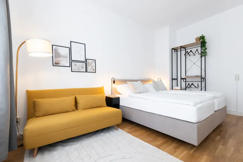 Schlafzimmer mit gelbem Sofa, Bogenleuchte und Doppelbett